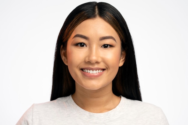 Ritratto di bella ragazza asiatica calma sorridente con lunghi capelli castani che guarda l'obbiettivo