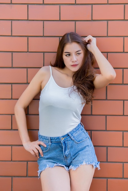 Ritratto di bella ragazza asiatica chic indossare abito nero posa per scattare una foto sul muro di mattoni Stile di vita della gente della Tailandia teenager Concetto felice della donna moderna