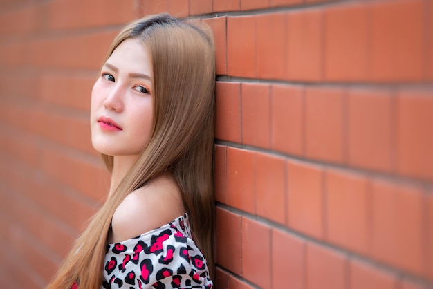 Ritratto di bella ragazza asiatica chic indossare abito nero posa per scattare una foto sul muro di mattoniStile di vita di giovani thailandesiLa donna moderna concetto feliceStile coreano