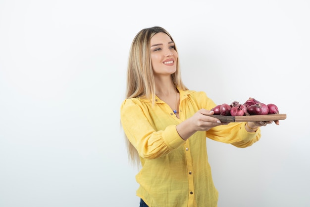 Ritratto di bella ragazza che tiene le cipolle rosse e in piedi