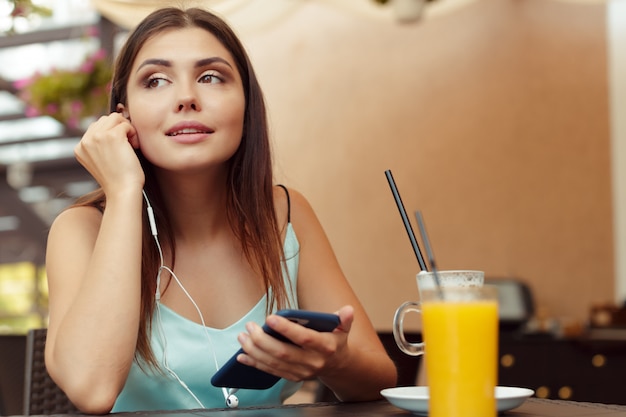 Ritratto di bella ragazza che utilizza il suo telefono cellulare nel caffè