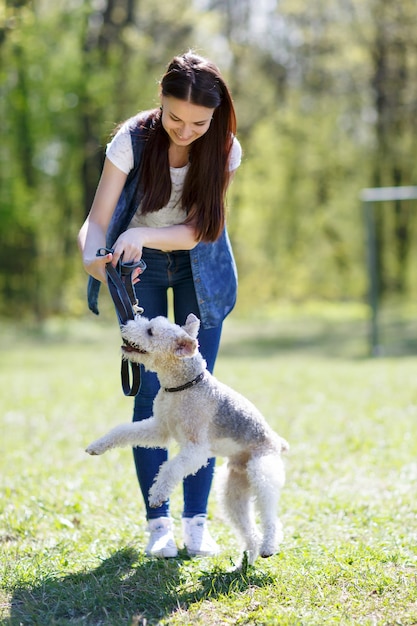 Ritratto di bella ragazza con il cane foxterrier all'aperto nel parco