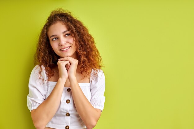 Ritratto di bella ragazza riccia piuttosto sognante pensando fantasticando isolato su sfondo verde