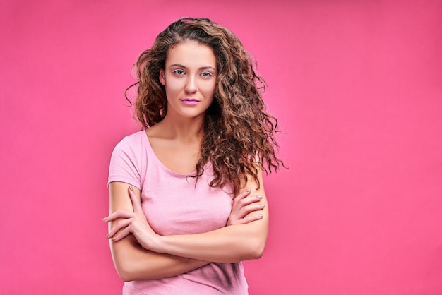 Ritratto di bella ragazza triste con acconciatura corta e trucco in maglietta rosa con le braccia incrociate