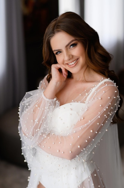 Ritratto di bella sposa con trucco da sposa nudo e acconciatura in abito elegante con perline Donna sorridente in posa e sorridente giorno del matrimonio previsto Perfetto modello di sposa caucasica