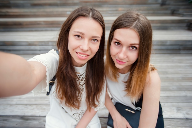 Ritratto di belle ragazze caucasiche che fanno selfie all'aperto. Giovani amici turistici che viaggiano in vacanza sorridendo felice.