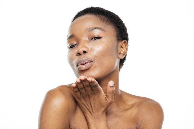 Ritratto di bellezza della donna afroamericana che soffia bacio alla telecamera isolata su uno sfondo bianco white