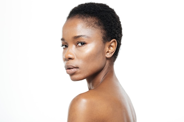Ritratto di bellezza della donna afroamericana con la pelle fresca che guarda l'obbiettivo isolato su uno sfondo bianco
