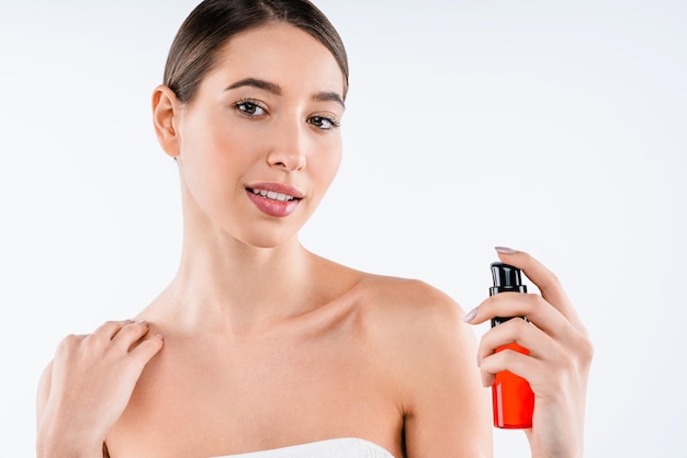Ritratto di bellezza della giovane donna attraente che mostra l'olio cosmetico in bottiglia isolato