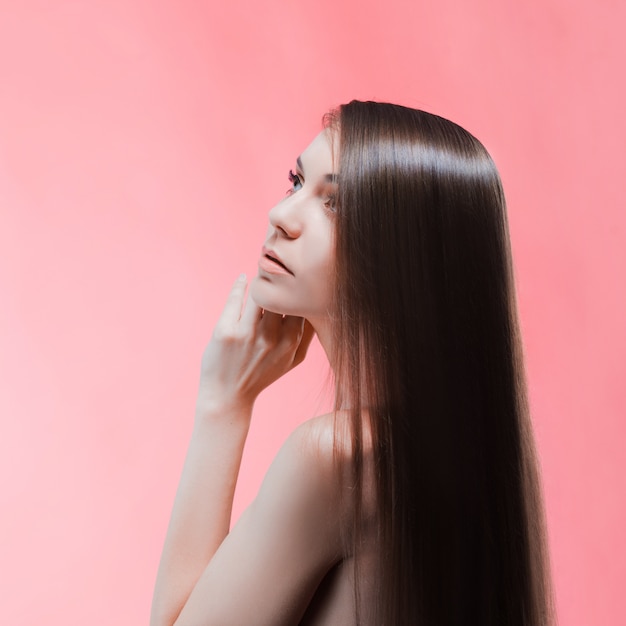 Ritratto di bellezza di bruna con i capelli perfetti, su una parete rosa. Cura dei capelli