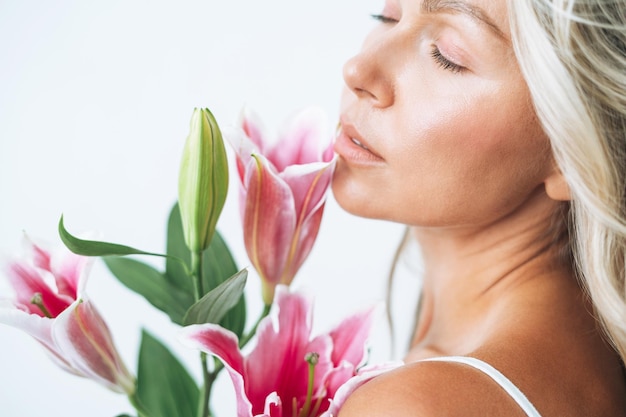 Ritratto di bellezza di capelli biondi sorridente giovane donna con giglio rosa in mano isolato su sfondo bianco