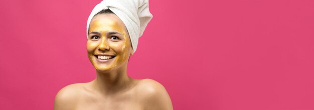 Ritratto di bellezza di donna in asciugamano bianco sulla testa con maschera nutriente dorata sul viso Pulizia della pelle eco-cosmetico biologico spa relax concept