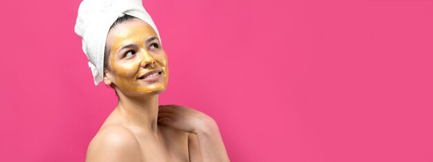 Ritratto di bellezza di donna in asciugamano bianco sulla testa con maschera nutriente dorata sul viso Pulizia della pelle eco-cosmetico biologico spa relax concept