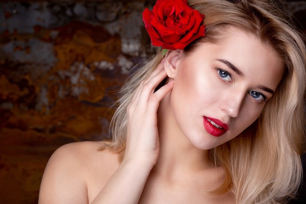 Ritratto di bellezza di giovane modella affascinante con le labbra rosse che posano allo studio con una rosa. Spazio per il testo