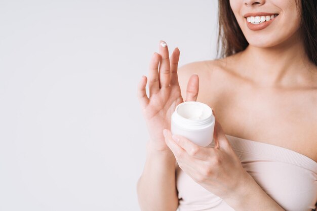 Ritratto di bellezza di una donna asiatica con la crema sulla pelle pulita e fresca viso e mani su sfondo bianco