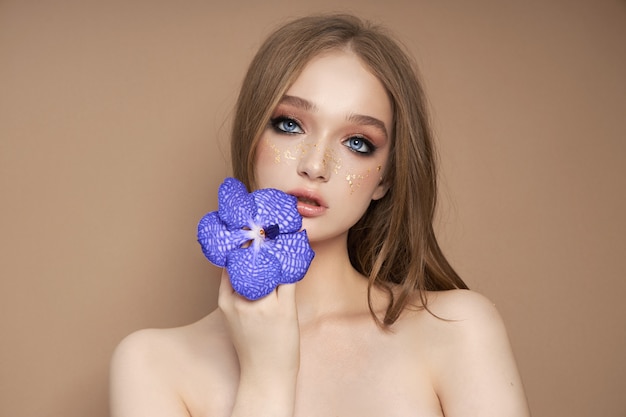 Ritratto di bellezza di una donna con una Vanda Orchid blu in mano.