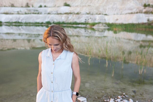 Ritratto di bellissima donna sorridente vicino a un lago con acqua leggera e colline sabbiose.