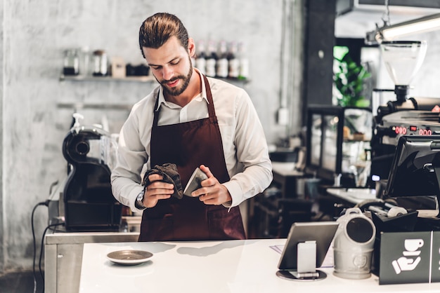 Ritratto di bello barbuto barista uomo piccolo imprenditore che lavora dietro il bancone in un bar