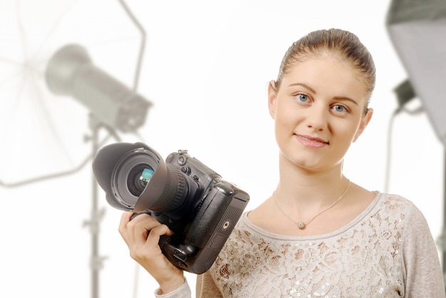 Ritratto di bello fotografo che sorride con la macchina fotografica digitale in studio