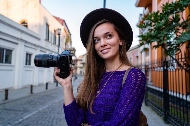 Ritratto di bello fotografo felice con la macchina fotografica alla via