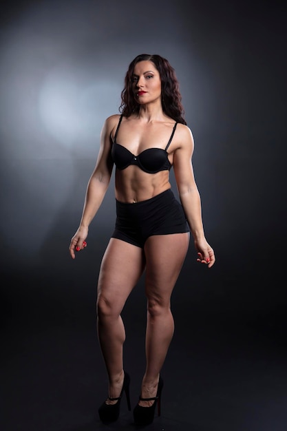 Ritratto di bodybuilder donna forte fitness con capelli neri e corpo abbronzato