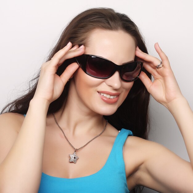 Ritratto di bruna con occhiali da sole su sfondo grigio