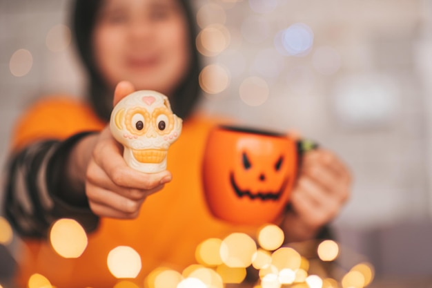 Ritratto di candido autentico zoomer ragazzo in posa con una tazza di tè e dolci a casa festa di Halloween