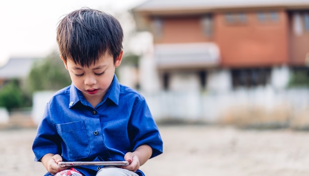 Ritratto di carino piccolo ragazzo asiatico rilassante utilizzando lo smartphone digitale.