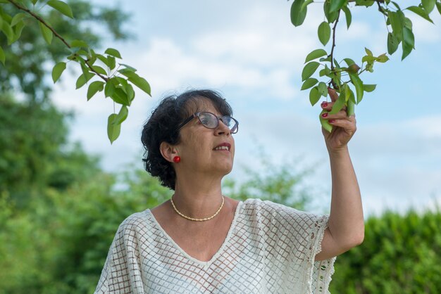 Ritratto di castana maturo con i vetri nel giardino