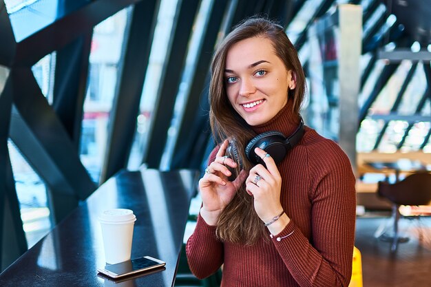 Ritratto di casual giovane sorridente felice gioiosa donna con cuffie senza fili.