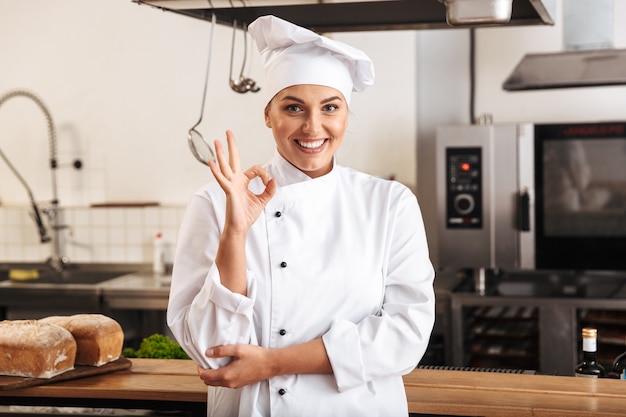 Ritratto di chef donna caucasica indossando l'uniforme bianca, in posa in cucina al ristorante