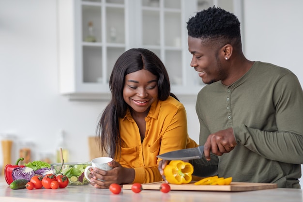 Ritratto di coniugi neri romantici che preparano cibo sano insieme in cucina