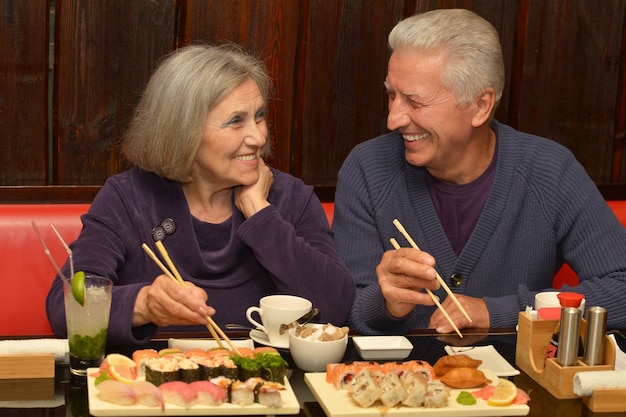 Ritratto di coppia di anziani che mangia sushi al bar