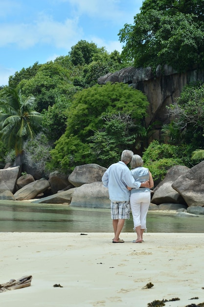 Ritratto di coppia di anziani che si abbracciano sulla spiaggia tropicale