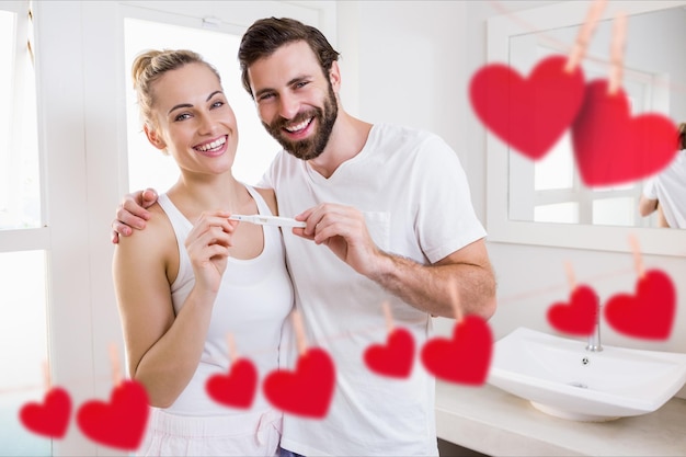 Ritratto di coppia felice che tiene il test di gravidanza in bagno