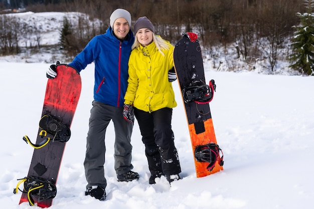 Ritratto di coppia felice di snowboarder fuori durante le vacanze invernali