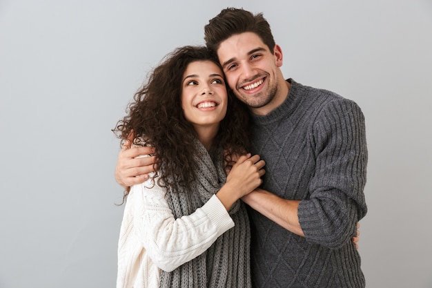 Ritratto di coppia felice uomo e donna sorridente mentre abbracciano insieme, isolato sopra il muro grigio