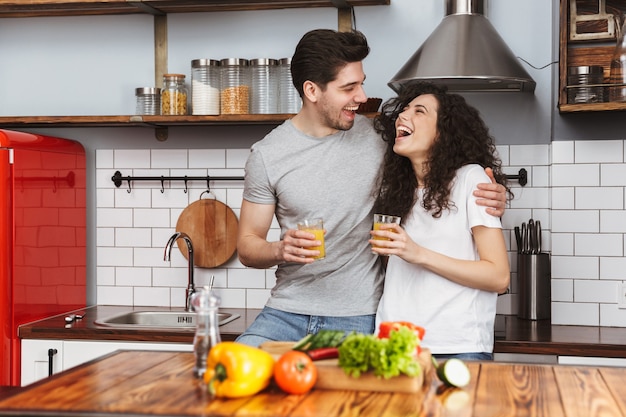 Ritratto di coppia ottimista uomo e donna che cucinano salat con verdure insieme mentre fanno colazione in cucina a casa