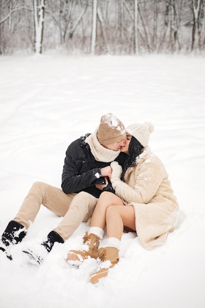 Ritratto di coppia romantica seduta su una neve nella foresta al giorno d'inverno