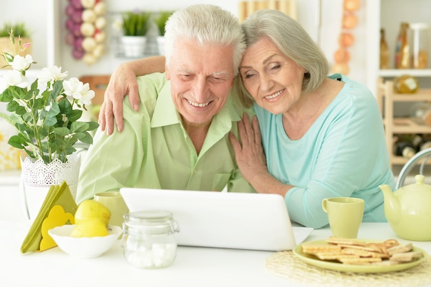 Ritratto di coppia senior con laptop a casa