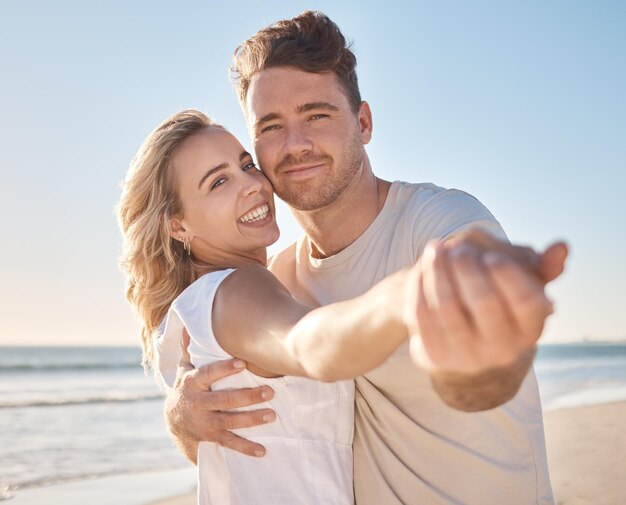 Ritratto di coppia sorriso e abbraccio per la cura dell'amore o il supporto durante le vacanze estive che si legano insieme in spiaggia Felice uomo e donna che si tengono per mano sorridendo per una vacanza di relazione sulla costa dell'oceano