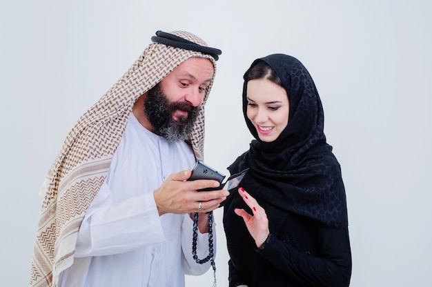 Ritratto di coppia vestita in modo arabo gioca con il telefono cellulare.