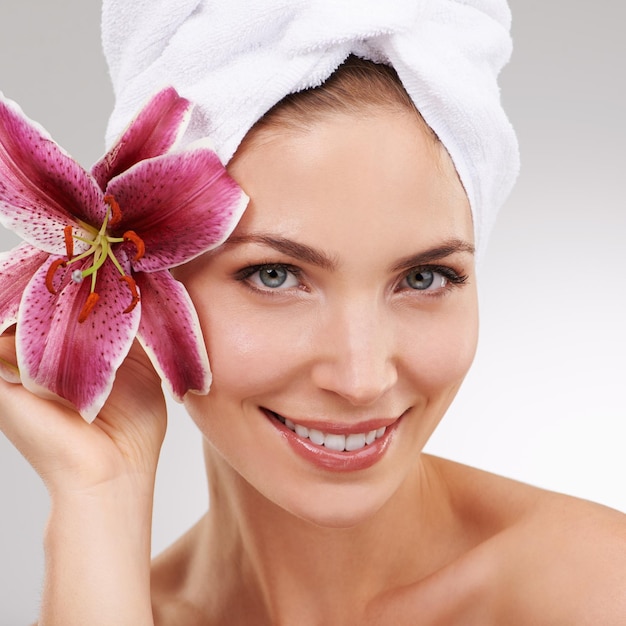 Ritratto di cura della pelle e donna con asciugamano fiore e trattamento spa con cosmetici in studio Dermatologia pelle sana e ragazza su sfondo bianco con salone di lusso faciale mattina e bellezza naturale