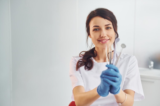 Ritratto di dentista professionista femminile con attrezzature che stanno al chiuso