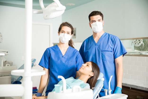 Ritratto di dentisti maschi e femmine in piedi accanto al paziente presso la clinica dentale