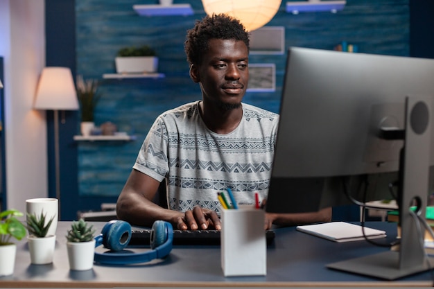 Ritratto di dipendente afroamericano che utilizza il computer mentre lavora a distanza da casa