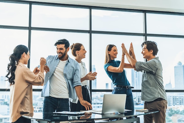 Ritratto di diversi professionisti della squadra di start-up che festeggiano il loro progetto Gruppo di uomini d'affari che applaudono cinque volte per festeggiare il nuovo prodotto sul tavolo con il laptop Tracery