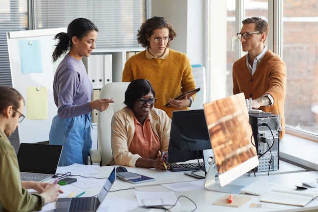 Ritratto di diversi team di sviluppo IT che utilizzano computer insieme mentre lavorano in uno studio di produzione software