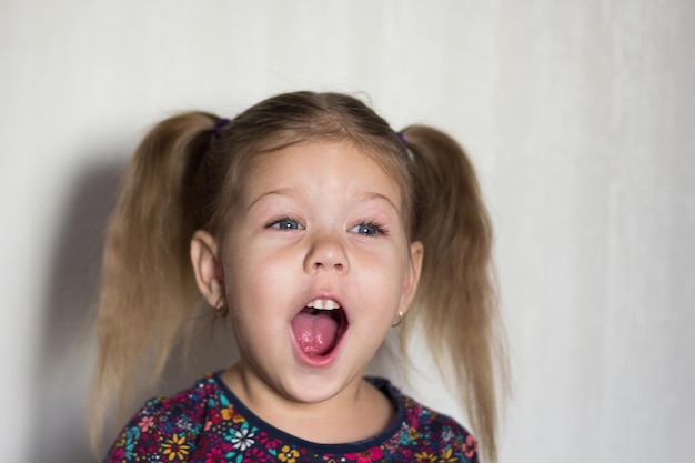 Ritratto di divertente felice caucasica di tre età bambina con la bocca aperta che guarda da parte sullo sfondo bianco