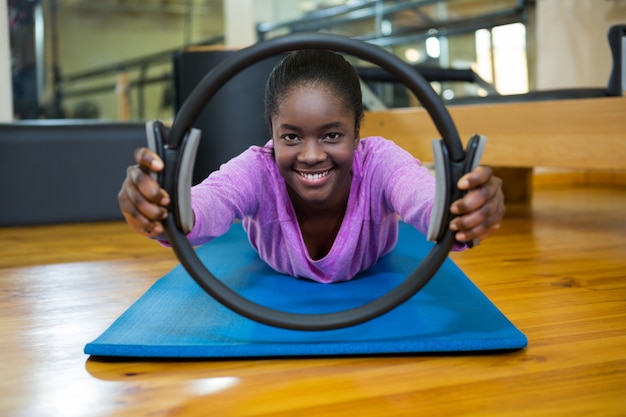 Ritratto di donna adatta che si esercita con anello di pilates in studio fitness